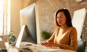 Asian businesswoman typing an email on desktop PC in the office
