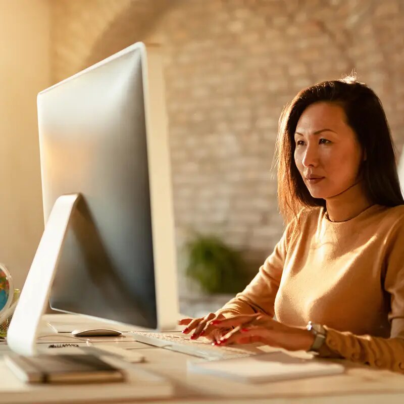 Asian businesswoman typing an email on desktop PC in the office