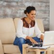 Cheerful woman waving during a video call while working from home.