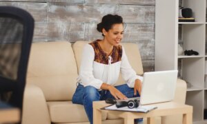 Cheerful woman waving during a video call while working from home.