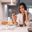 Woman's morning with phone,croissant and coffee at kitchen